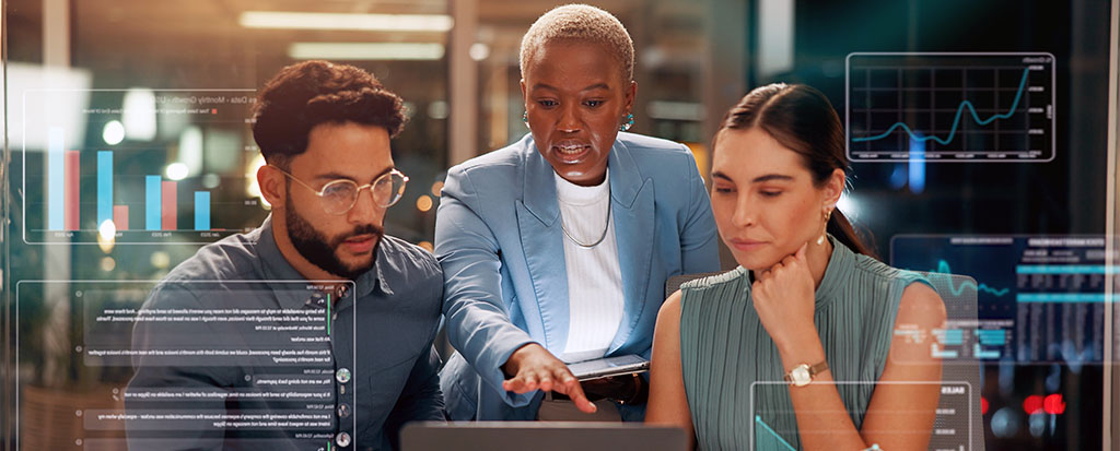 Three professionals reviewing charts and statistics in a modern office environment
